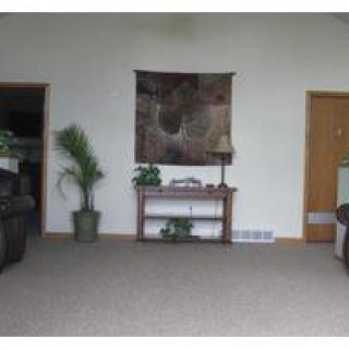 A cozy living room with a table, wall art, and potted plants.