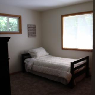 A minimalist bedroom with a single bed and two windows.