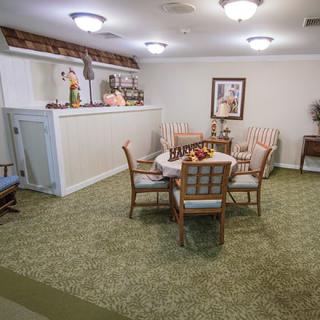 A cozy living area with a round table surrounded by chairs, decorative items, and soft lighting.