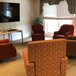 A cozy seating area with armchairs arranged around a television in a well-lit room.