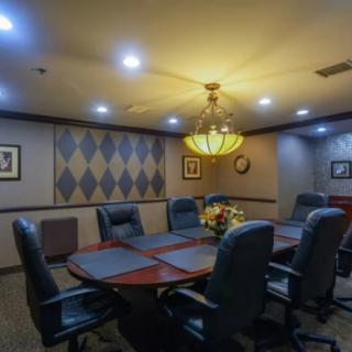 A dimly lit conference room with a large table and chairs, decorated with artwork on the walls.