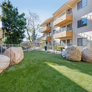 A residential apartment complex featuring a well-maintained lawn and large decorative rocks in the outdoor area.