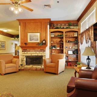 A cozy living room with a fireplace, armchairs, and a bookshelf.
