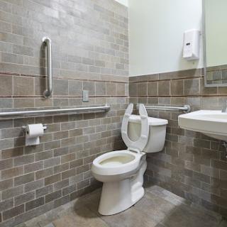 A clean and accessible bathroom featuring a toilet, sink, and grab bars.