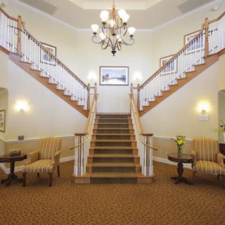 A grand interior featuring a symmetrical staircase with elegant chandeliers and comfortable seating.