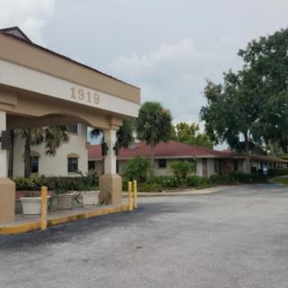 An exterior view of a building with an entrance and a surrounding parking area on an overcast day.