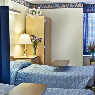 A hospital room with two beds, medical furniture, and decorative elements.