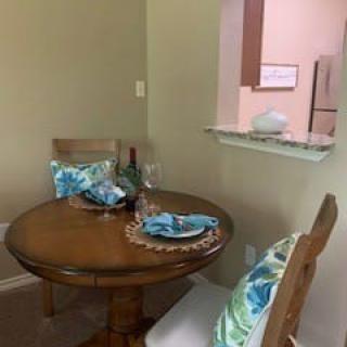 A cozy dining area with a round wooden table set for two.