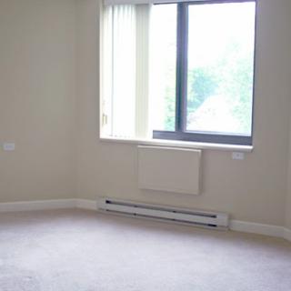 A bright, empty room featuring a large window and neutral-colored walls.