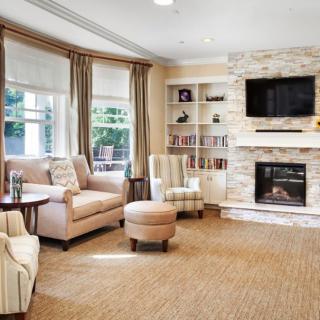 A cozy and modern living room with a fireplace, sleek furniture, and large windows.