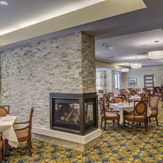 Cozy dining room featuring a central fireplace and elegantly arranged tables and chairs.