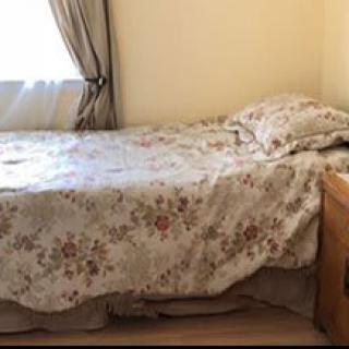 A cozy bedroom with a single bed featuring floral bedding and curtains.