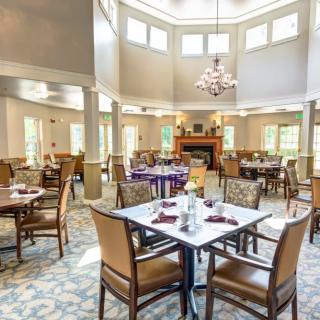 An elegant dining room with neatly arranged tables and chairs under a chandelier.