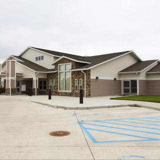 A modern building with a parking lot on a cloudy day.