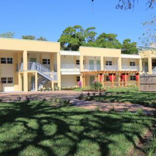 A two-story residential building with a well-maintained lawn and trees.