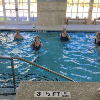A group of women participating in a water aerobics class in an indoor pool.