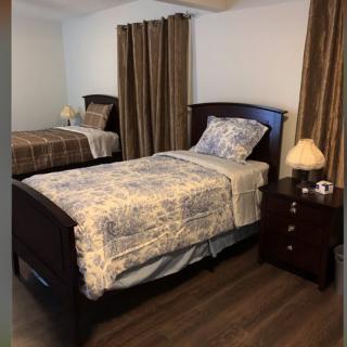 A cozy bedroom with two twin beds, a nightstand, and lamps.