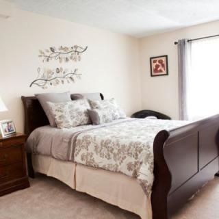 A cozy bedroom with elegant furniture and tasteful decor featuring a large wooden bed, neatly arranged bedding, and decorative wall art.