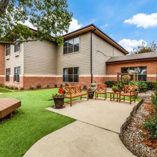 A well-maintained building with a landscaped garden featuring a pathway, benches, and lush green lawn.