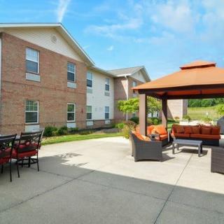 A cozy outdoor patio area with comfortable seating under a gazebo, adjacent to a brick building on a sunny day.