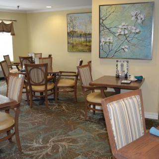 A cozy dining room with wooden chairs and tables, decorated with artwork on the walls.