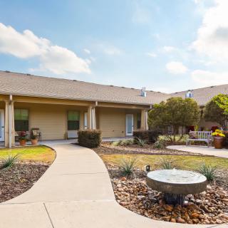 A well-maintained courtyard with a walking path and garden area in front of a building.