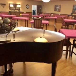 A cozy dining area with a grand piano and tables.