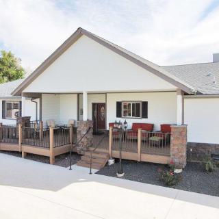 A residential house with a welcoming porch and deck, featuring outdoor seating and brick accents.
