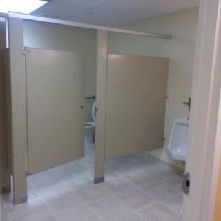 A public restroom with two stalls and a urinal.