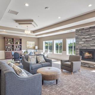 A modern living room with a cozy seating area, featuring a fireplace and large windows.