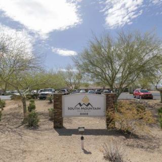 A desert landscape with a sign and parking lot on a cloudy day.