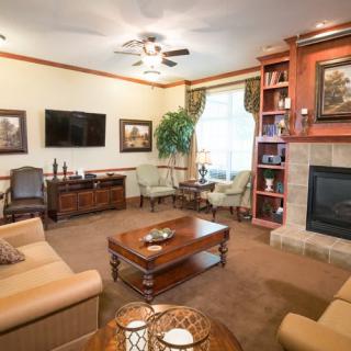 A cozy living room with warm lighting, featuring a comfortable seating area, a fireplace, and elegant decorations.