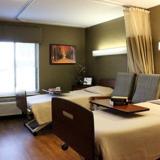 A modern hospital room with two patient beds and medical equipment.