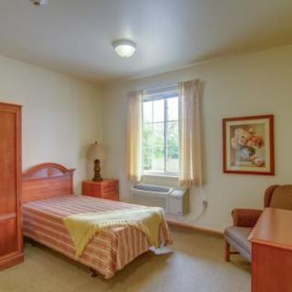 A cozy single bedroom with simple furnishings and a window allowing natural light.