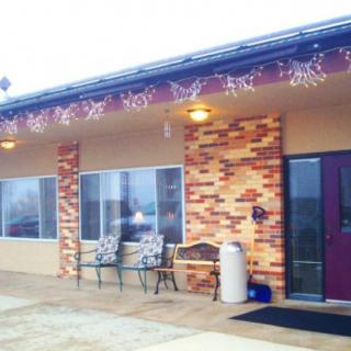 A small building entrance with outdoor seating and decorative lights.