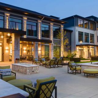 A modern luxury building with outdoor seating and evening lighting.