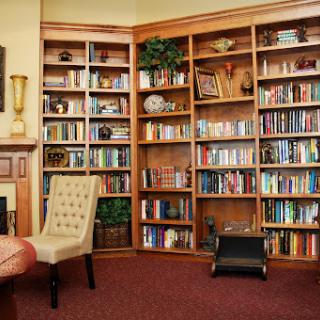 A warm and inviting corner of a library featuring wooden bookshelves filled with a variety of books, accompanied by comfortable seating.