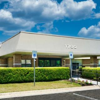 A commercial building with accessible parking spots in front under a partly cloudy sky.