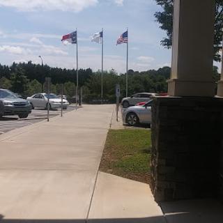 A view of a parking lot with flags flying in the background under a clear sky.