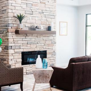 A modern living room with a stone fireplace and cozy seating.