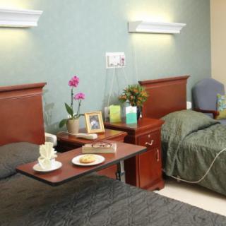 A comfortable hospital room with two beds, bedside tables, and decorative elements.