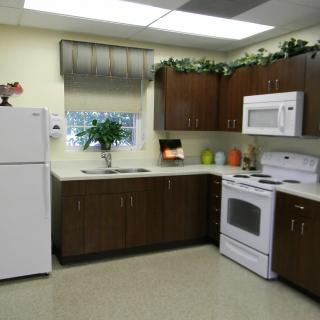 A modern kitchen with wooden cabinets, a refrigerator, stove, and microwave.