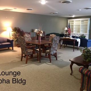 A cozy lounge area with a table, chairs, sofas, and carpeted flooring.