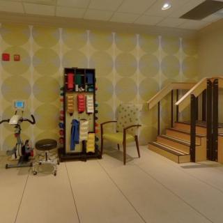 A physical therapy room with various exercise equipment and a small staircase for rehabilitation exercises.
