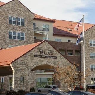 A modern hotel with a stone facade and flags at the entrance.
