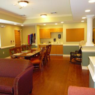 A communal living area featuring a dining table, kitchen, and lounge seating.