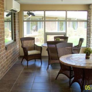 A cozy indoor patio area featuring wicker furniture and large windows.