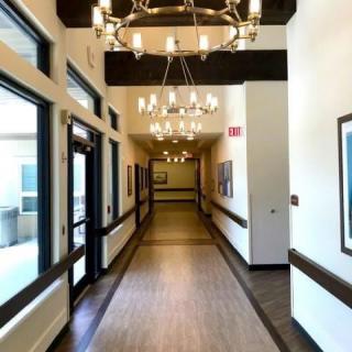 A well-lit hallway with chandeliers and windows along the side.