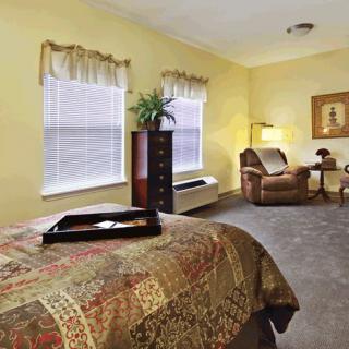 A cozy bedroom with a bed, armchair, and decorative elements.