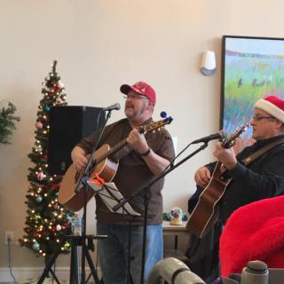 Musicians perform with guitars during a festive holiday gathering.